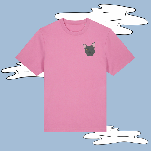 A pink short-sleeve crewneck t-shirt featuring a small cartoon French Bulldog graphic on the left chest, displayed against a light blue background with white cloud illustrations.